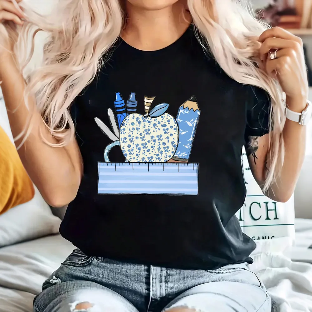 An Apple With A Blue Flower Pattern Surrounded By Stationery, Including Blue Crayons, Pencils, Scissors And Paper Clips, And A Light Blue Ruler At The Bottom, With A Casual T-Shirt.