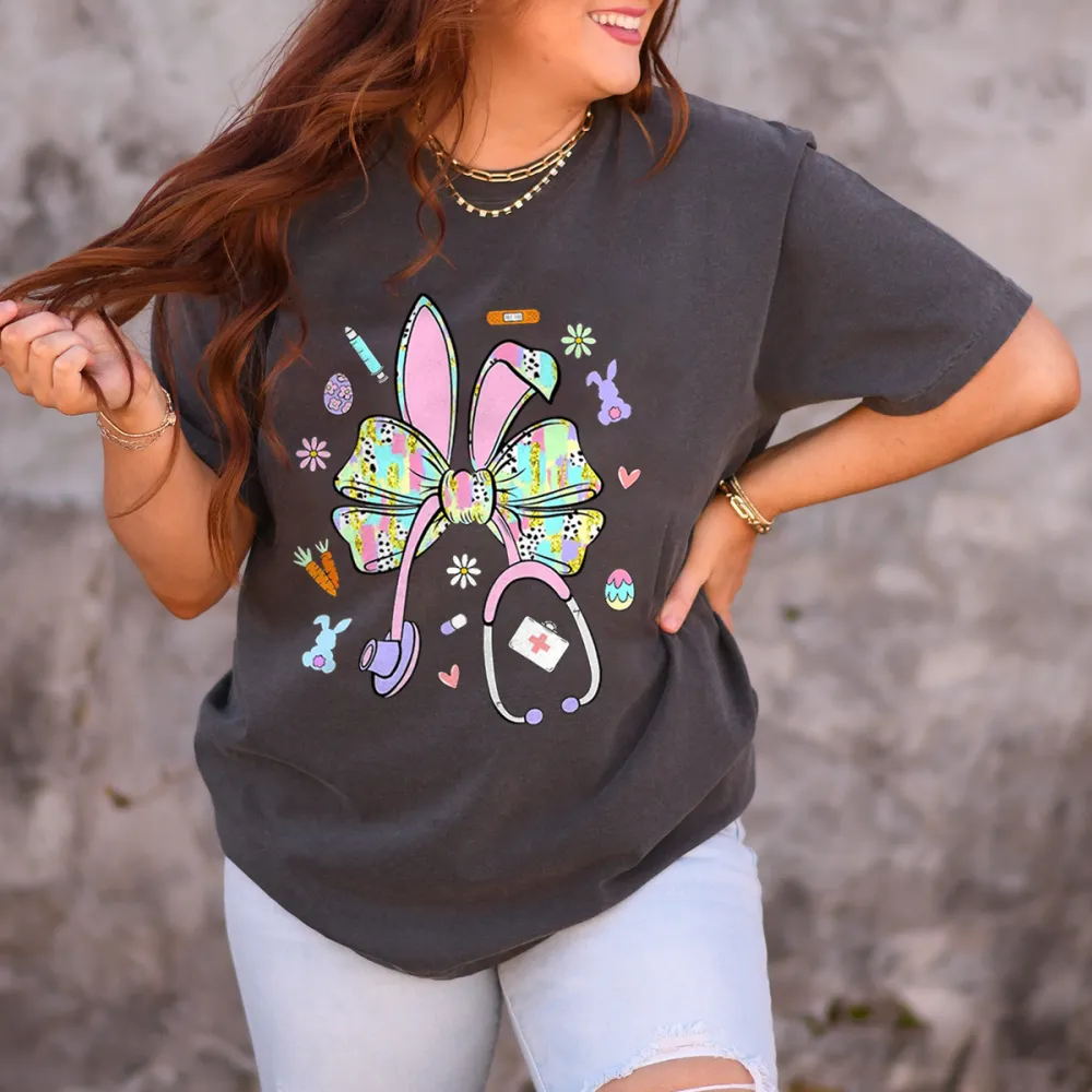 A Bow Pattern With Rabbit Ears, Patterns Of Various Colors On The Bow And Ears, Pencils, Rabbits, Small Flowers, Eggs, Stethoscopes, Heart Shapes, Full Of Childlike Fun, Casual T-Shirt