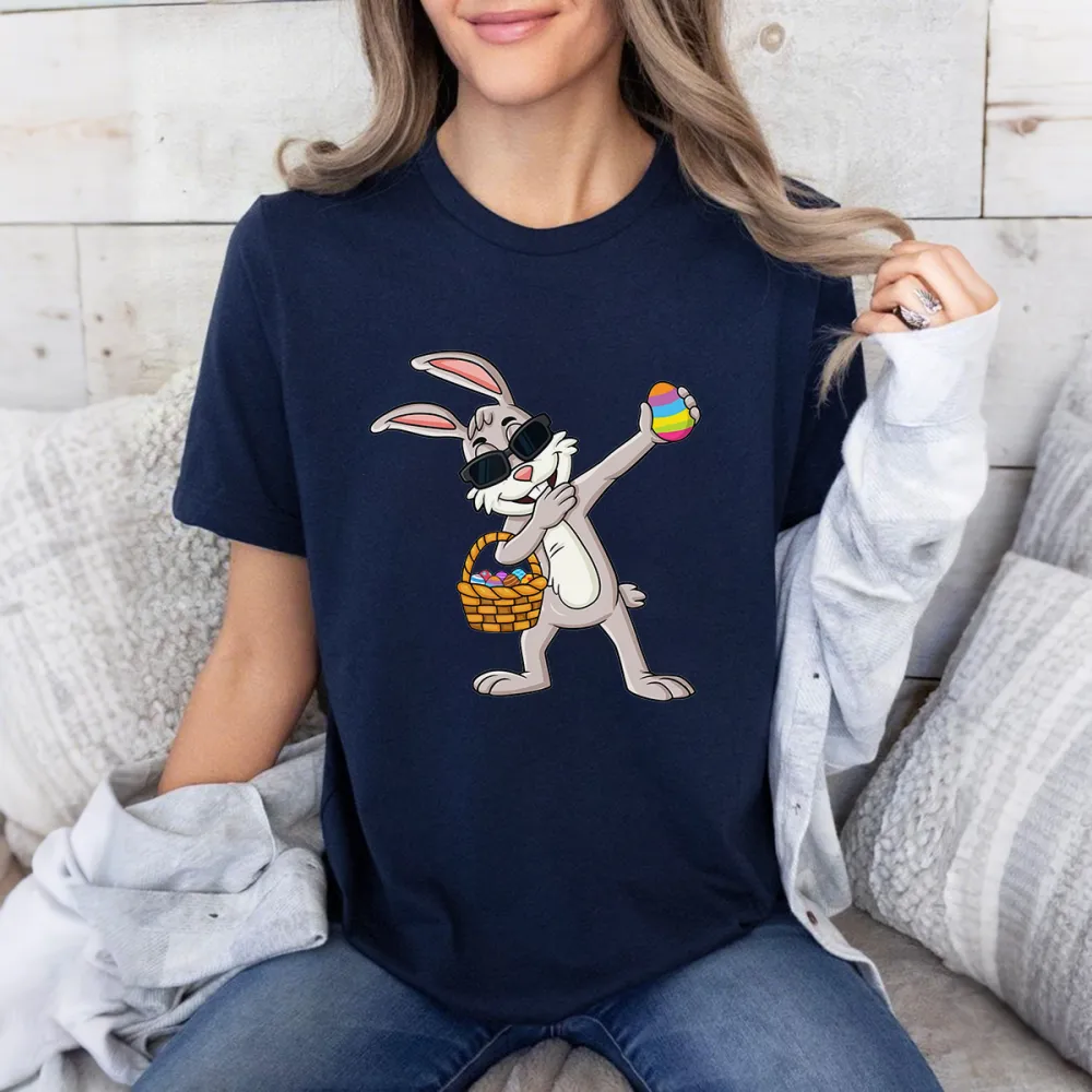 A Cartoon Rabbit Wearing Black Sunglasses, Holding A Colorful Easter Egg, With A Basket Full Of Eggs Next To The Other Hand. The Style Is Playful And Cute, With A Casual T-Shirt.