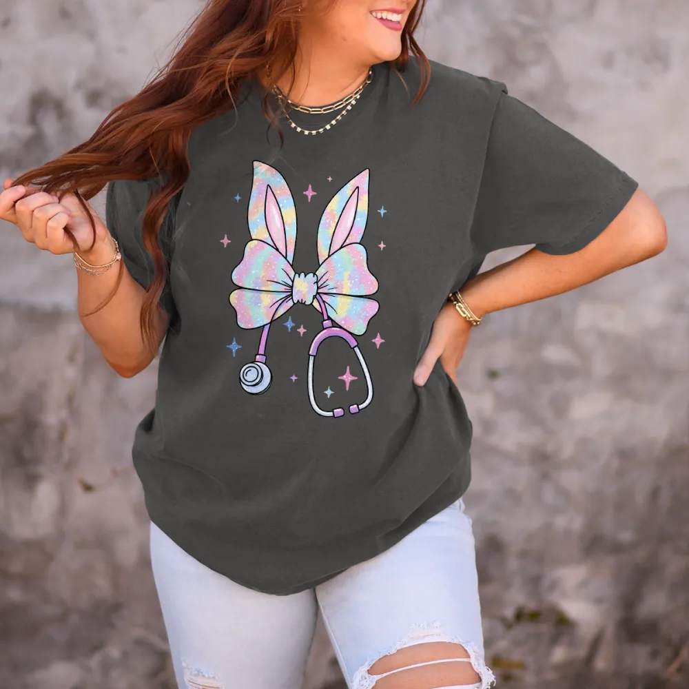 A Bow Pattern With Bunny Ears, With Gradient Effects Of Pink, Blue, Purple And Other Colors On The Bow And Ears, A Stethoscope, And Stars Dotted Around It, Cute Style, Childlike, Casual T-Shirt