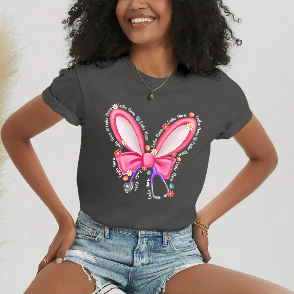 Repeating “Easter Nurse” Multiple Times, The Slogan Is Wrapped Around Pink Cartoon Bunny Ears And Bows, A Stethoscope, And Is Dotted With Small Flowers And Gems, And A Casual T-Shirt.
