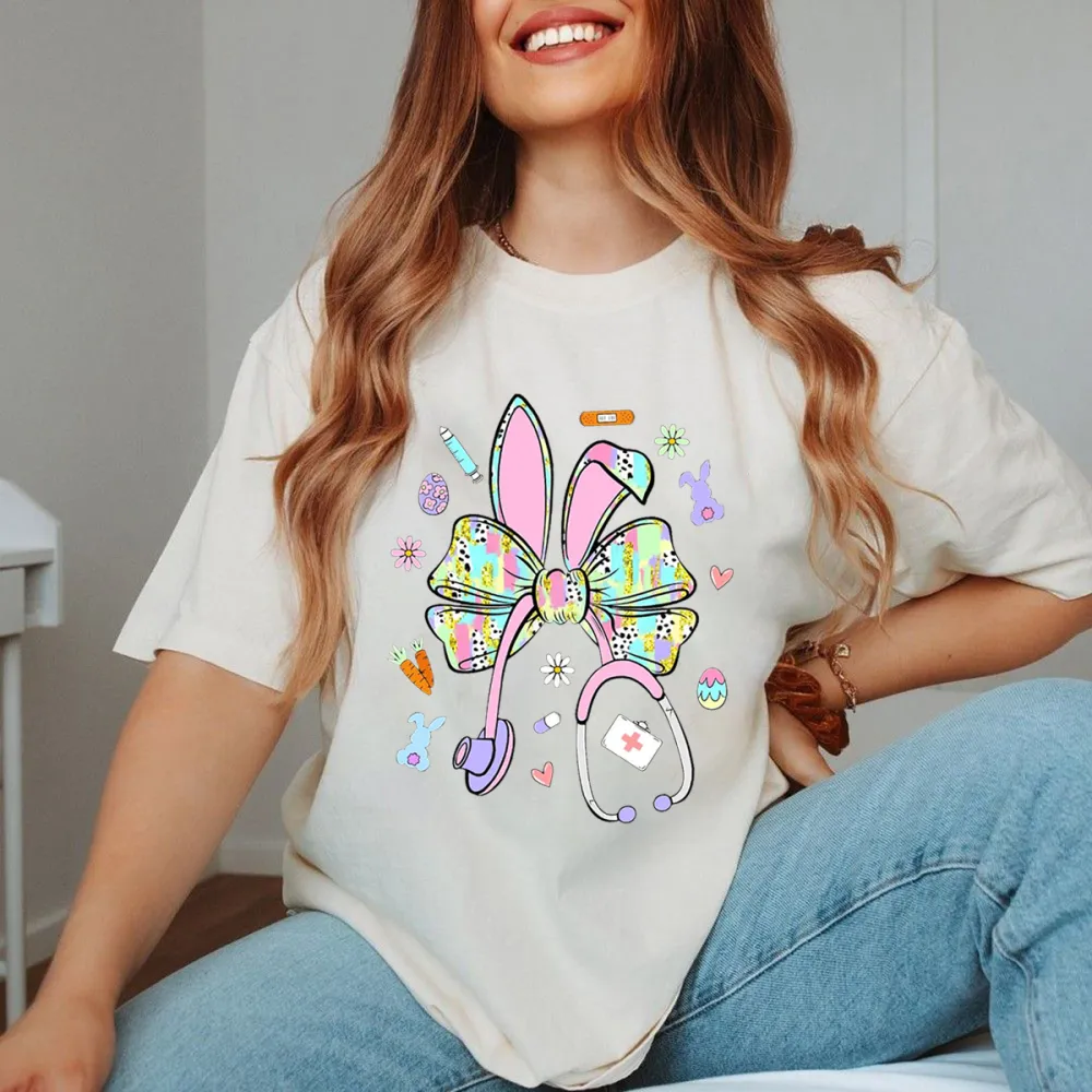 A Bow Pattern With Rabbit Ears, Patterns Of Various Colors On The Bow And Ears, Pencils, Rabbits, Small Flowers, Eggs, Stethoscopes, Heart Shapes, Full Of Childlike Fun, Casual T-Shirt