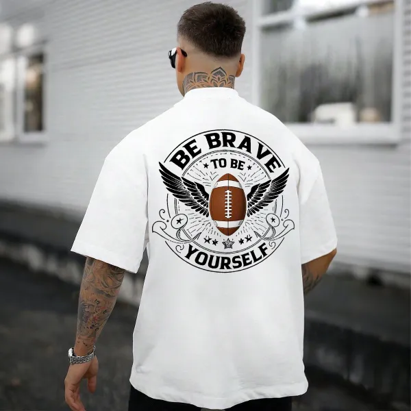 This Is A Graphic T-Shirt With Sports And Inspirational Elements. There Is A Rugby Ball In The Middle And Wings On Both Sides. The Words 