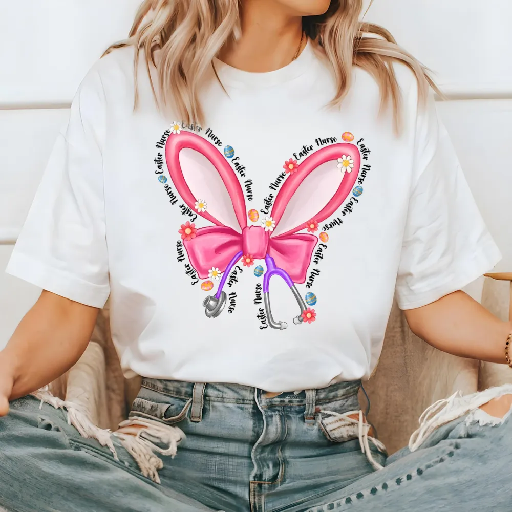 Repeating “Easter Nurse” Multiple Times, The Slogan Is Wrapped Around Pink Cartoon Bunny Ears And Bows, A Stethoscope, And Is Dotted With Small Flowers And Gems, And A Casual T-Shirt.