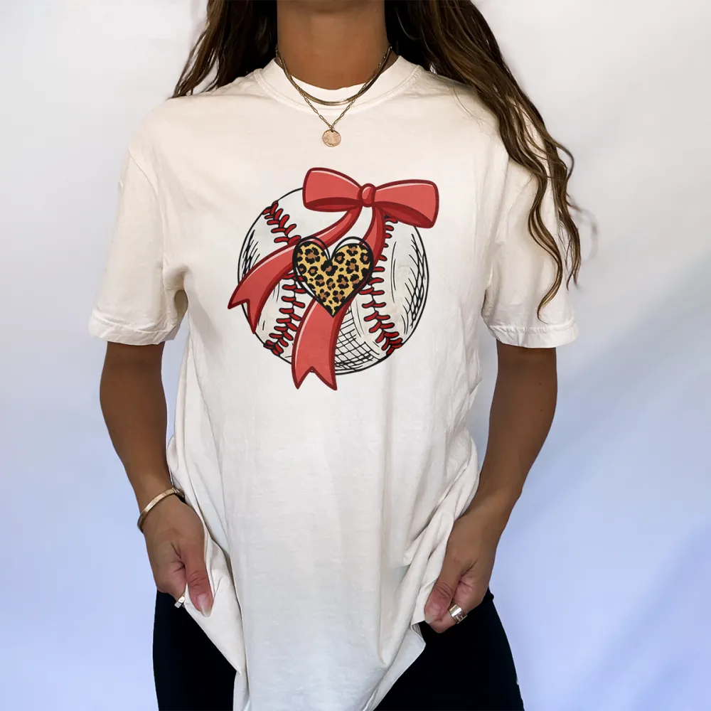A Pattern Combining A Stitched Baseball, A Red Bow And A Leopard Print Heart. There Is Also A Leopard Print Heart Pattern On The Ball, A Casual T-Shirt.