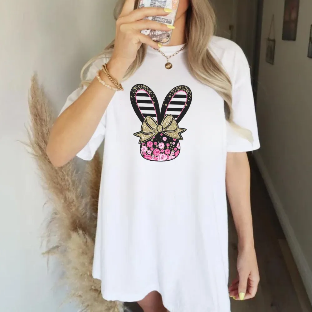 Cartoon Style Bunny Ears Pattern, The Ears Are Black And White Stripes, Tied With A Golden Bow With A Floral Pattern, And A Vase Covered With Pink Flowers, A Casual T-Shirt.