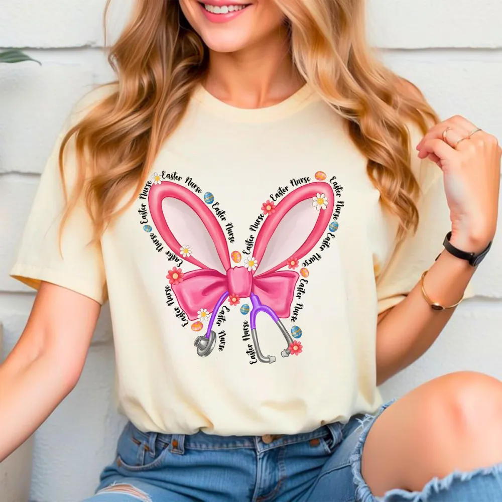 Repeating “Easter Nurse” Multiple Times, The Slogan Is Wrapped Around Pink Cartoon Bunny Ears And Bows, A Stethoscope, And Is Dotted With Small Flowers And Gems, And A Casual T-Shirt.
