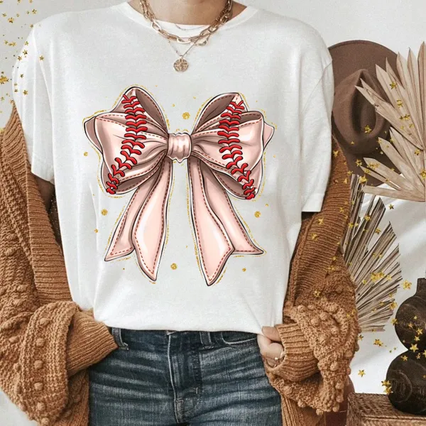 A Light Pink Bow Pattern With Red Baseball-Like Stitching Elements On The Edge Of The Bow And Some Gold Dots Around It, A Casual T-Shirt.